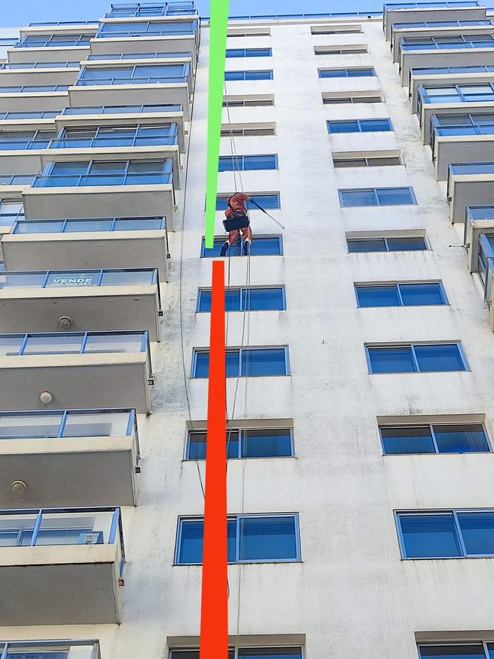 Torre Amadeus con un operario en cuerda: arriba la fachada blanca limpia, abajo con manchas