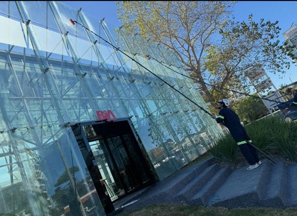 Operario limpiando una fachada de vidrio con pértiga